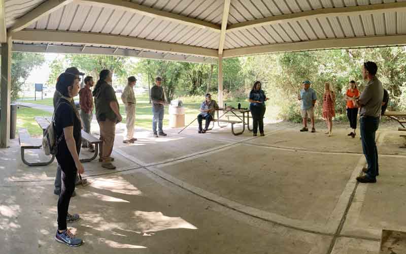 Photo of people outside listening to a presentation