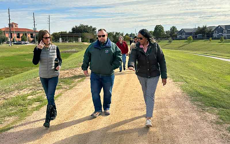 Three people walking on a dirt trail