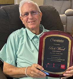 Photo of Mr. Bob Wood showing off a retirement award plaque