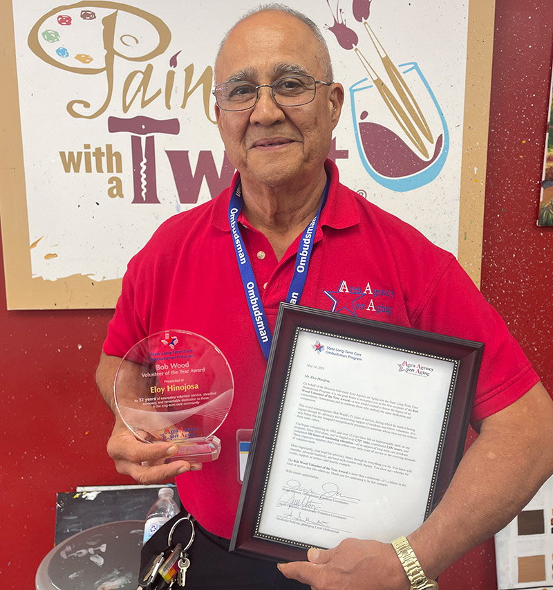 Recipient Mr. Eloy Hinojosa holding the Bob Wood Volunteer of the Year Award and a framed and signed award letter
